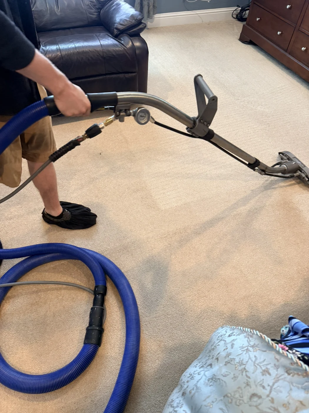 Technician extracting a carpet beside cleaning hoses